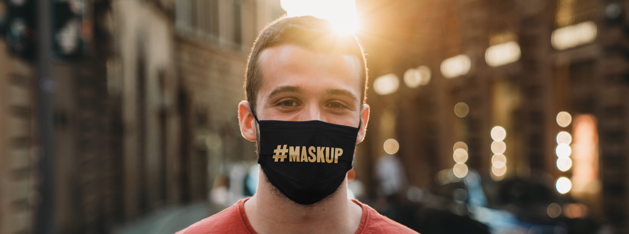 Portrait of a young adult man wearing a protective face mask and looking at camera