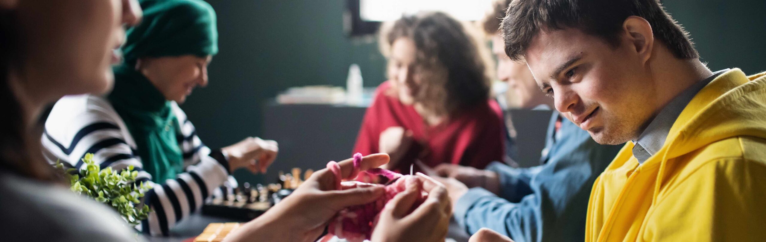Group of people playing cards and board games in community center, inclusivity of disabled person.