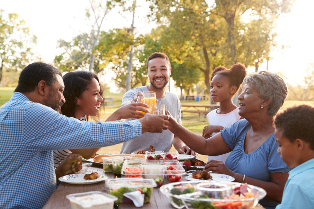 Multi Generation Family Enjoying Picnic In Park Together